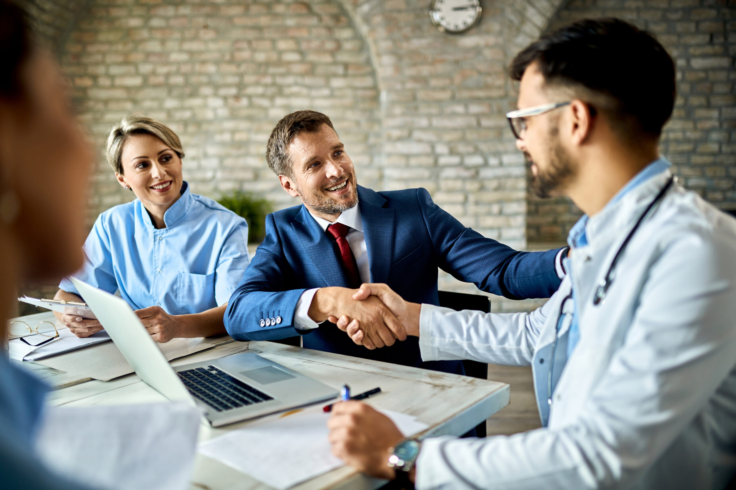 Happy Financial Advisor Male Doctor Shaking Hands After Successful Meeting Office Scaled